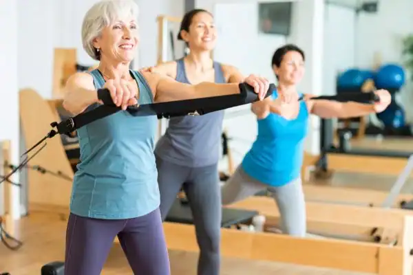 Toning Arms After 60: Empowering Womens Fitness Through Effective Weight Training 2 older woman doing weight training Bridport and resistance in the gym to tone upper arms